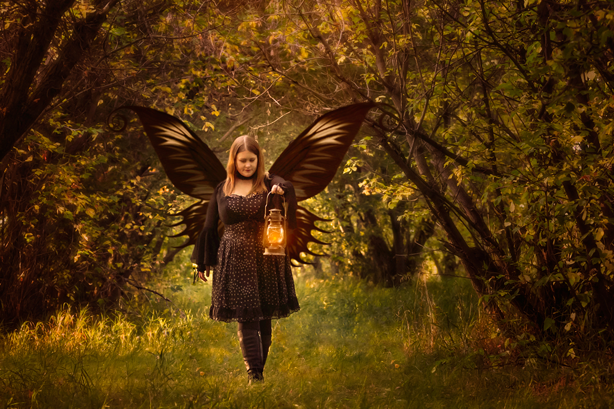 Jenn, maker of Lunahrin Candles, in a wooded clearing holding a lit lantern